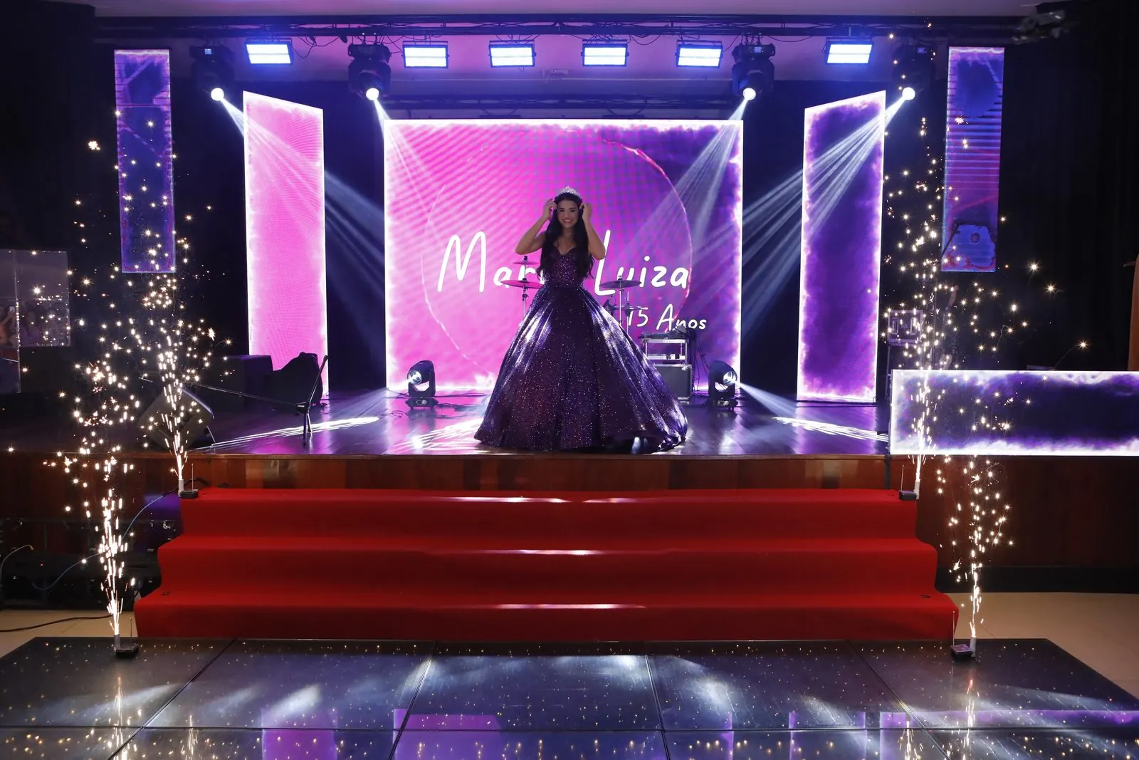 Debutante no palco do Salão Social, com telões e chuva de prata