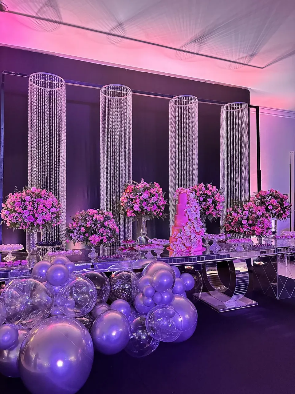Mesa do bolo decorada com flores e balões metalizados