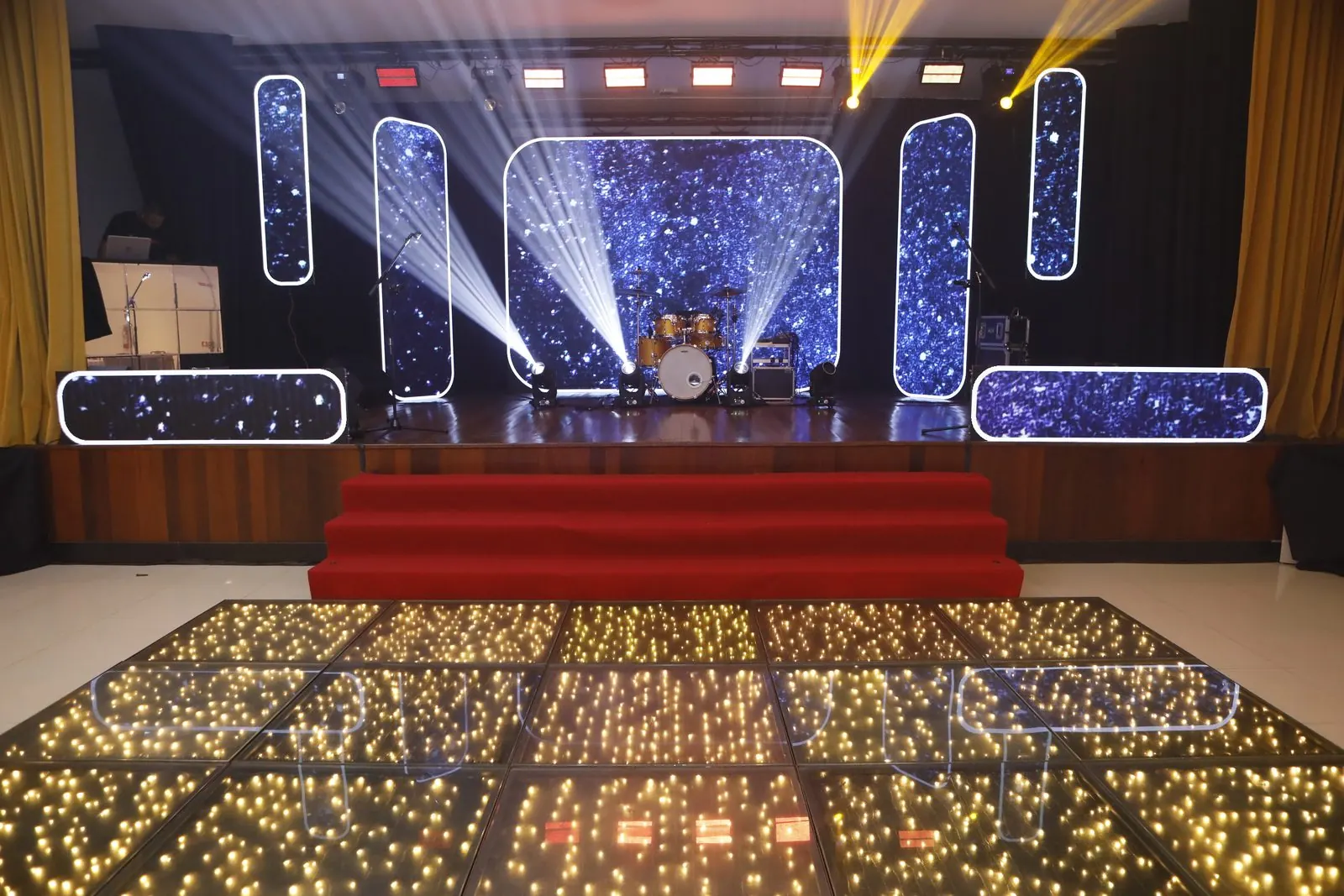 Palco iluminado e pista de LED prontos para a festa