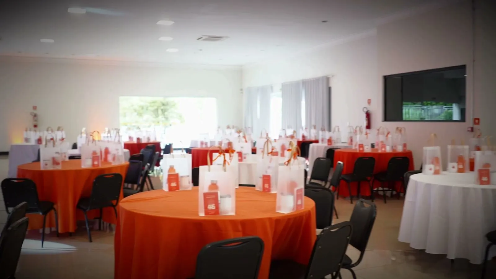 Salão montado com mesas redondas para evento corporativo